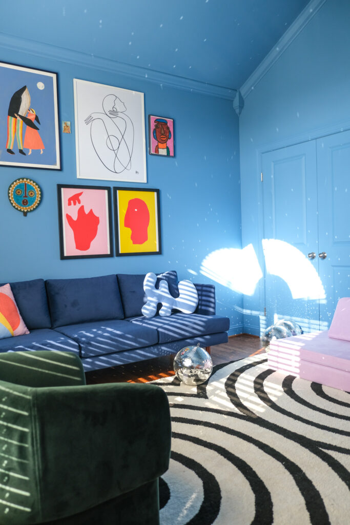 room painted blue with gallery wall and black and white rug